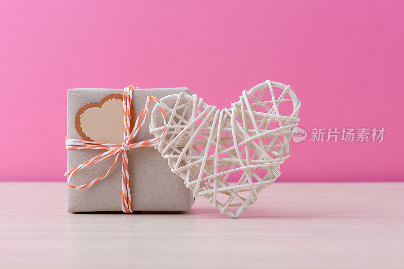 Craft handmade gift box and valentineâs heart over pink background with copy space